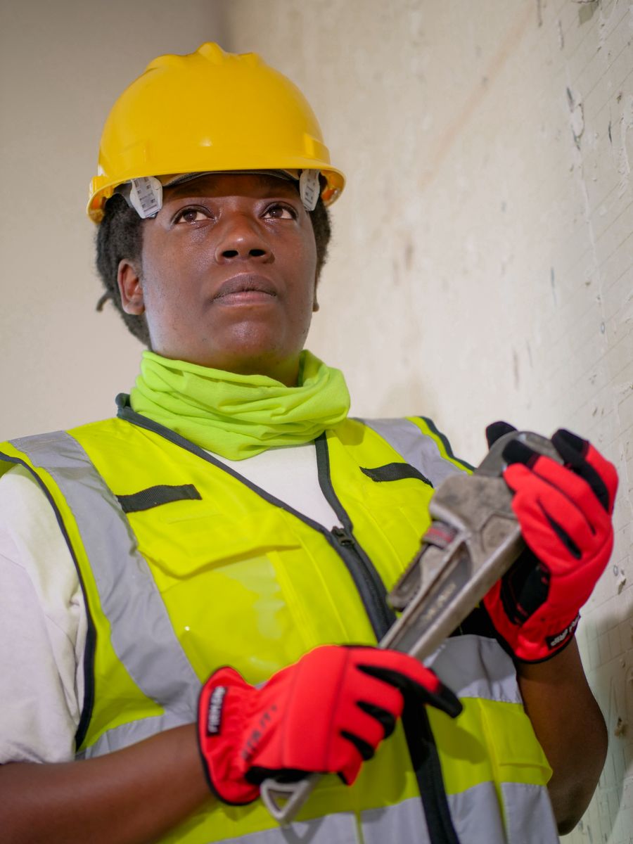 Copperline plumber in a high-visibility vest holding a pipe wrench